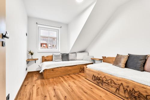 two beds in a room with white walls and wooden floors at Residence Koubek - stylové apartmány s parkováním in Boží Dar
