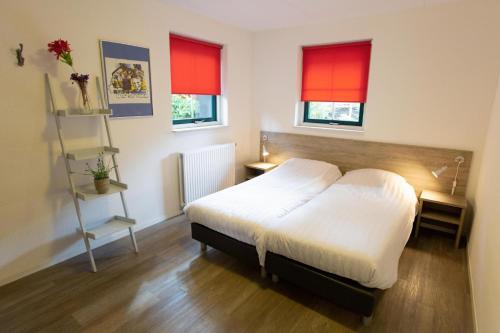 une chambre avec un lit blanc et des fenêtres rouges dans l'établissement Vennenhof Bungalow Deluxe | 6 personen, à Hooghalen