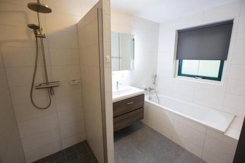 une salle de bain avec une baignoire, un lavabo et une douche dans l'établissement Vennenhof Bungalow Deluxe | 6 personen, à Hooghalen