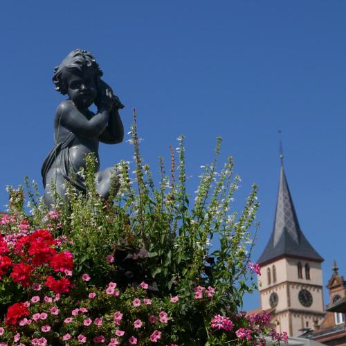 a statue in front of a building with a clock tower at Le Bacchus in Barr