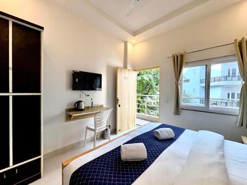 a bedroom with a bed and a desk and a window at Zuna Stayz Tapovan Rishikesh in Rishīkesh