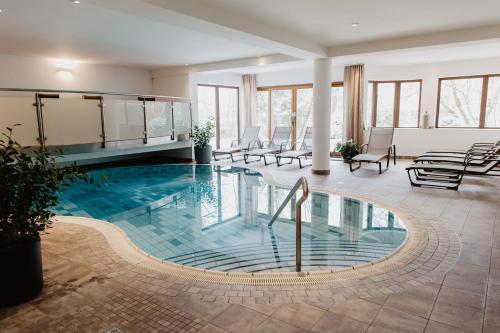 a pool in a hotel lobby with chairs and tables at Hotel Hubertus in Lofer