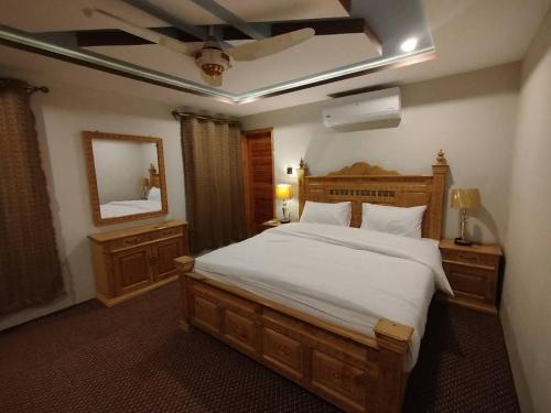 Un dormitorio con una gran cama blanca y un espejo. en Crown Resort, en Skardu