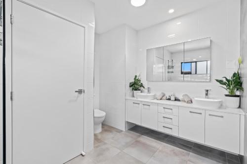een witte badkamer met 2 wastafels en een toilet bij Laid-Back Wurtulla Escape with Style & Charm in Kawana Waters