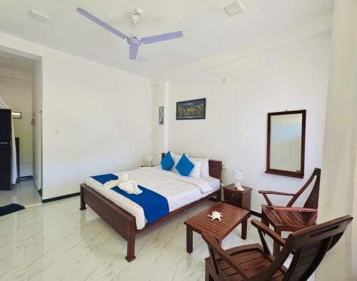 a bedroom with a bed and two chairs and a mirror at AP Pearl Palace -Tangalle in Tangalle