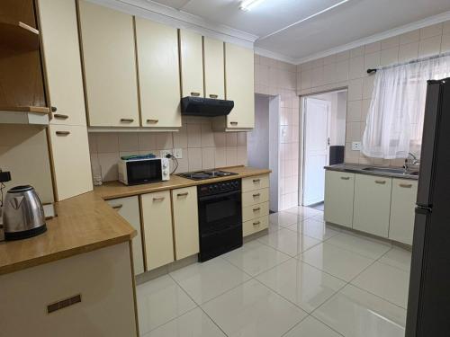 a kitchen with white cabinets and a black stove top oven at Mitchell Guest House Golf Road in Pietermaritzburg