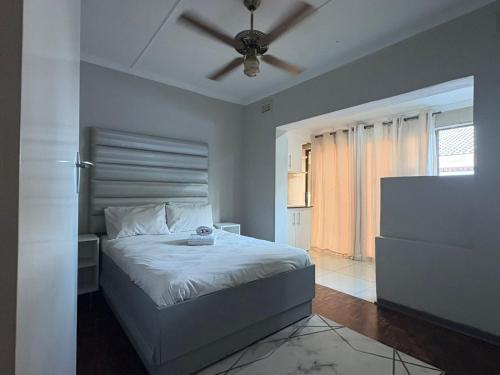 a bedroom with a bed with a ceiling fan at Mitchell Guest House Golf Road in Pietermaritzburg