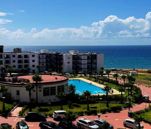 a view of a resort with a pool and the ocean at Atlantique Assilah Vue Mer, Piscines, Clim & Wi-Fi in Asilah