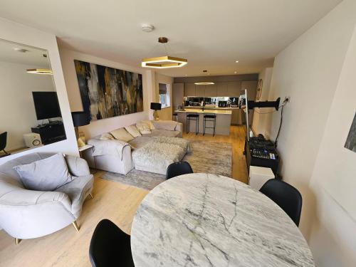 a living room with couches and a table and a kitchen at Luxury 2 double bedroom Apt in the heart of Purley in Purley