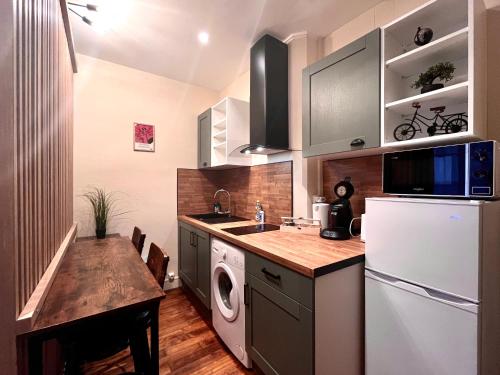 a kitchen with a white refrigerator and a table at La Pause - 15m2 - central - proche parking in Auxerre
