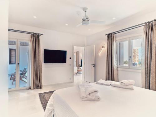 a white bedroom with a bed and a tv at Villa Raphael - Luxury and Serenity in Paros in Naousa