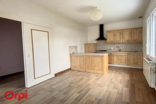 an empty kitchen with wooden cabinets and a wooden floor at L'Arbre de Vie in Montmarault