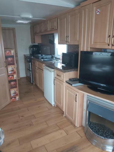 eine Küche mit Holzschränken und einem großen TV in der Unterkunft The Chase Caravan Park Ingoldmells ref EE in Skegness