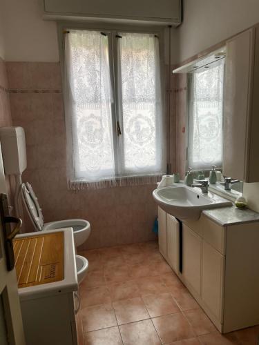 a bathroom with a sink and a toilet and windows at A casa della nonna in Imola