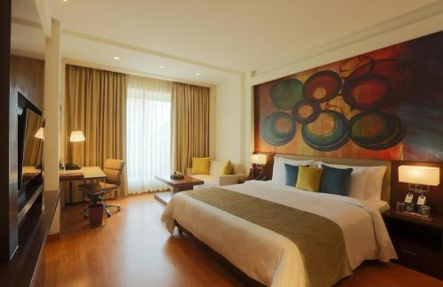 ニューデリーにあるHotel Park Tree Near Airport Delhiのベッドと壁に絵が飾られたホテルの部屋