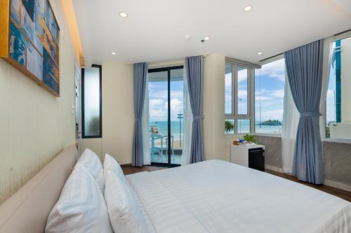 une chambre avec un grand lit et de grandes fenêtres dans l'établissement ONE SEASON BOUTIQUE HOTEL Vung Tau - BEACHFRONT, à Vung Tau