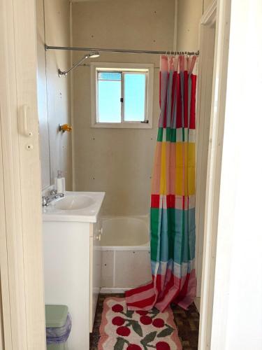 a bathroom with a rainbow shower curtain next to a sink at Marlins Beach Shack Broulee in Broulee