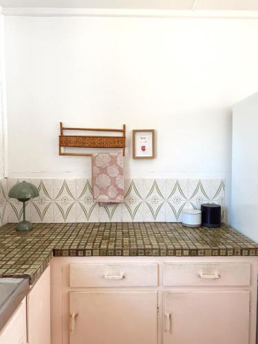 a kitchen with a counter top and tiles on the wall at Marlins Beach Shack Broulee in Broulee