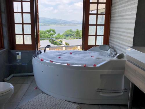 een groot bad in een badkamer met een raam bij Bush Baby View Lodge in Hartbeespoort