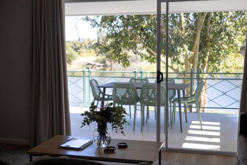 ein Wohnzimmer mit einem Tisch und Stühlen auf dem Balkon in der Unterkunft Patryssenvalleij Farm and Cottages in Stellenbosch