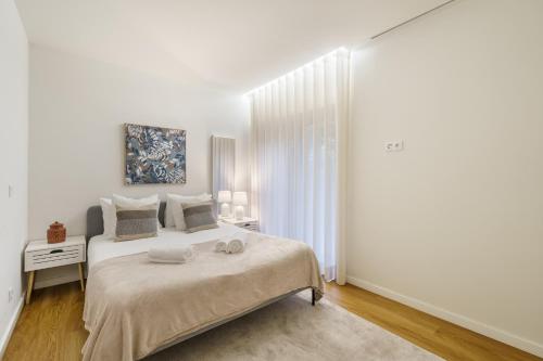 a white bedroom with a large bed and a window at Casa do Alcaide - Minhos Guest in Braga