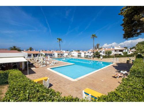 een zwembad in een resort met stoelen en palmbomen bij Appartamento Safir Son Bou con vista mare e piscina in Son Bou