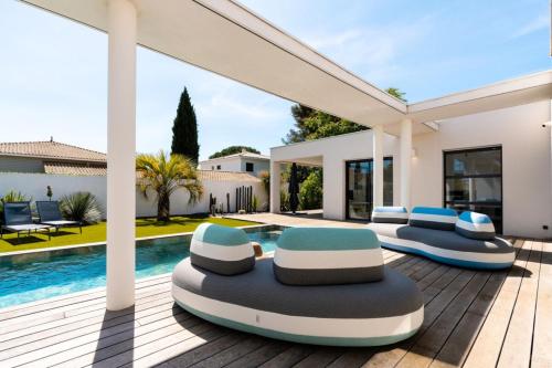 une villa avec une piscine et deux chaises longues dans l'établissement Villa Boston luxury home with pool and Cali vibes, au Grau-dʼAgde