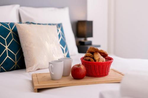 - un plateau avec une pomme et 2 tasses sur le lit dans l'établissement Villa Paulina village heart near the beaches, à Portiragnes