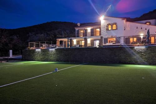 a house with a tennis court at night at Mas Sureda Soccer field & indooroutdoor pools in Argelès-sur-Mer