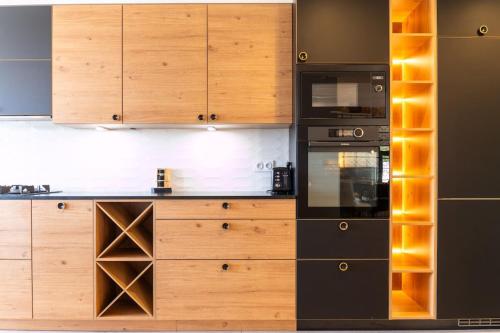 a kitchen with wooden cabinets and black appliances at Mas Sureda Soccer field & indooroutdoor pools in Argelès-sur-Mer