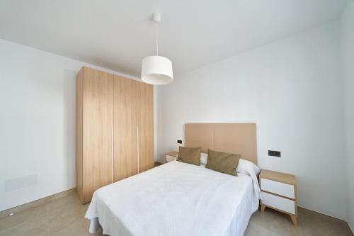 een slaapkamer met een wit bed en een houten kast bij Eryan II in San José