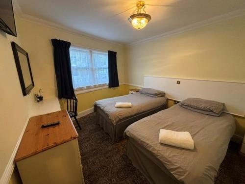 a hotel room with two beds and a desk at Hotel de Ville in Ramsgate