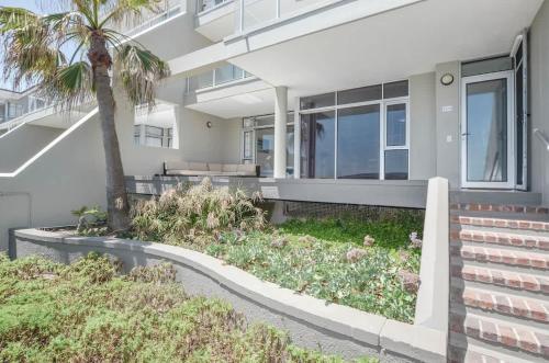 una casa con una palma di fronte di Spacious Beach Access Apartment at Dolphin Beach a Bloubergstrand