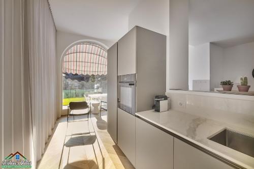 kuchnia z białymi szafkami i krzesłem w obiekcie APT in Villa Bianca with Pool and air conditioning w mieście Lierna