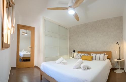 una camera da letto con un letto con lenzuola bianche e un ventilatore a soffitto di Habana en el corazón de Cuenca a Cuenca