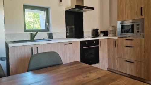 eine Küche mit Holzschränken, einem Tisch und einer Mikrowelle in der Unterkunft Maisonnette du Foirail in Espalion