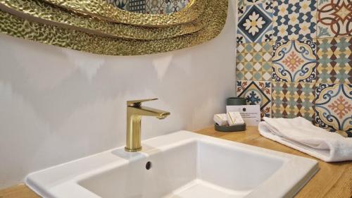 a white sink with a gold faucet in a bathroom at Maisonnette du Foirail in Espalion