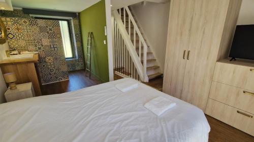 a bedroom with a white bed and a staircase at Maisonnette du Foirail in Espalion