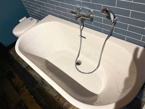 a bath tub with a faucet and a toilet at Le Garage - logement insolite à 2 pas de Lille in Sainte-Marguerite