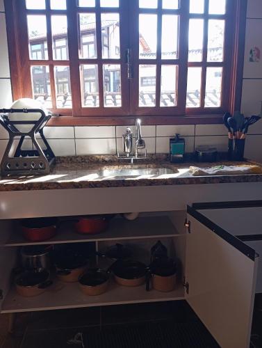 a kitchen counter with a sink and some windows at Chalé da Lili in Nova Friburgo