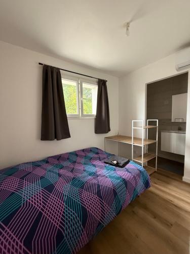 a bedroom with a colorful bed and a kitchen at Studio Coloc in Villenave-dʼOrnon