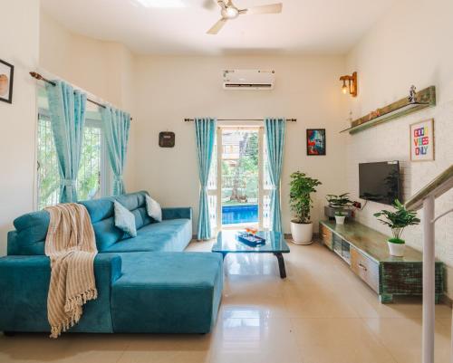 a living room with a blue couch and a tv at Villa Sylvana By Bluewave Hospitality in Nagoa-Bardez