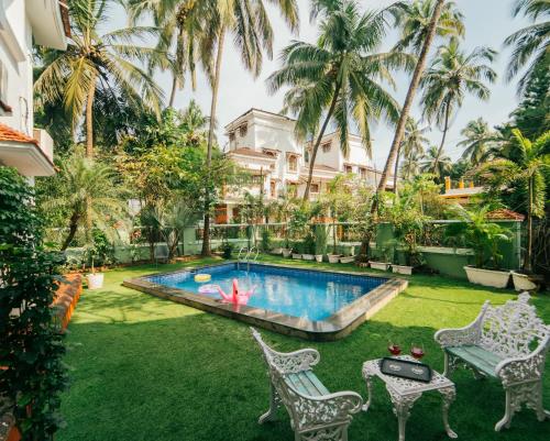 a backyard with a swimming pool and palm trees at Villa Sylvana By Bluewave Hospitality in Nagoa-Bardez