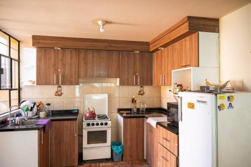 a kitchen with wooden cabinets and a white refrigerator at Namaste Bnb in Yanahuara