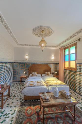 a bedroom with a large bed and a table at Riad Al Mozyane in Fez