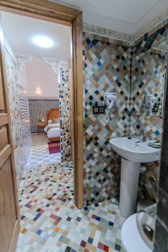 a bathroom with a sink and a mosaic tile wall at Riad Al Mozyane in Fez