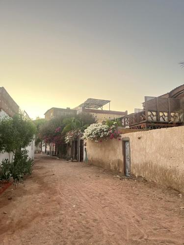 a dirt road next to a building with flowers at Ge boho house in Dahab
