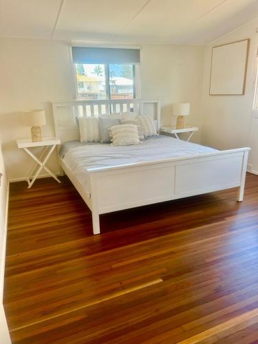 a large white bed in a room with wood floors at Seeside Cottage - Sleeps 6 & Pets in Bargara