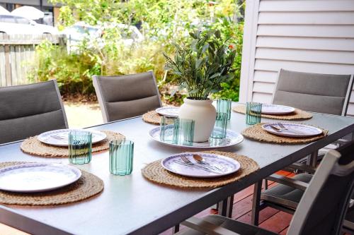 a table with plates and glasses and a vase at Seeside Cottage - Sleeps 6 & Pets in Bargara