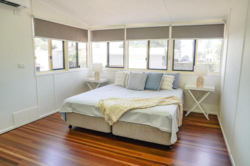 a bedroom with a bed with two tables and windows at Seeside Cottage - See St Bargara in Bargara